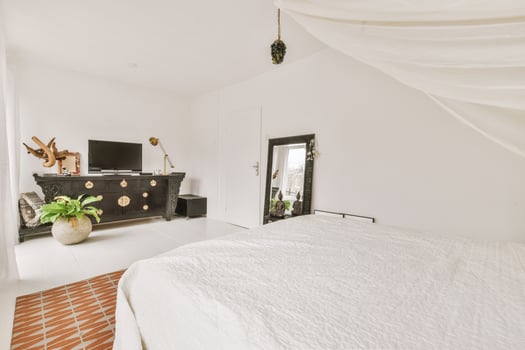 A white bedroom with a bed and a television photo