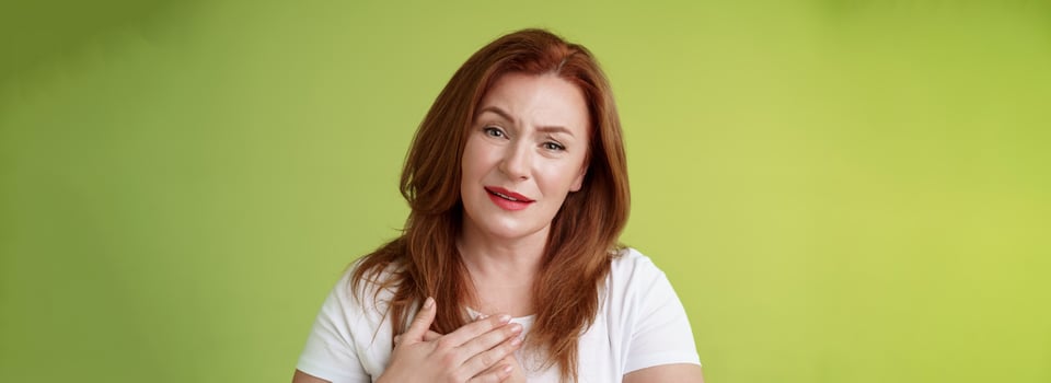 Story touched lady heart. Tender impressed middle-aged redhead woman press palms chest sighing happily look heartwarming temptation smiling appreciate nice gesture grateful thanking dearly photo