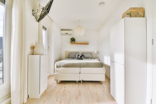 A bedroom with a bed, a television and a window photo