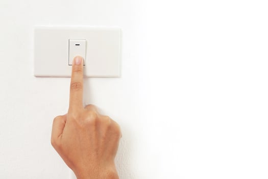 Turn off the light, close up female hand is closing the power switch. Save energy, reduce global warming. photo