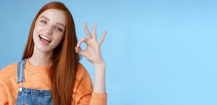 Studio shot carefree happy attractive european redhead girl show okay ok sign smiling white teeth approval confirmation recommend good product agree terms give positive feedback, think idea perfect photo