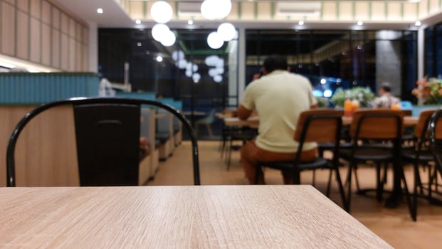 Blurry background of restaurant with wooden table in front for displaying product photo