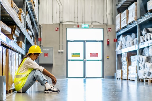 Young asian woman warehouse worker staff feeling sad and upset or look tired and lost job while sitting on the floor of the storehouse due to been fired from job cause by company bankruptcy photo