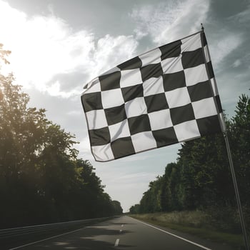 Checkered flag waves over a straight road bordered by lush trees For Social Media Post Size photo