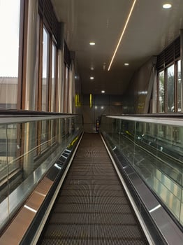 Modern Indoor Walkway with Glass Railings and Bright Lighting Leading to an Urban Transportation Hub photo