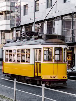 A bright yellow vintage tram moving through the streets of Lisbon photo