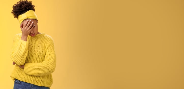 Upset tired african-american female entrepreneur facepalm bow head close eyes palm pressed face embarrassed stupid inappropriate behaviour drunk coworker standing annoyed irritated yellow background photo