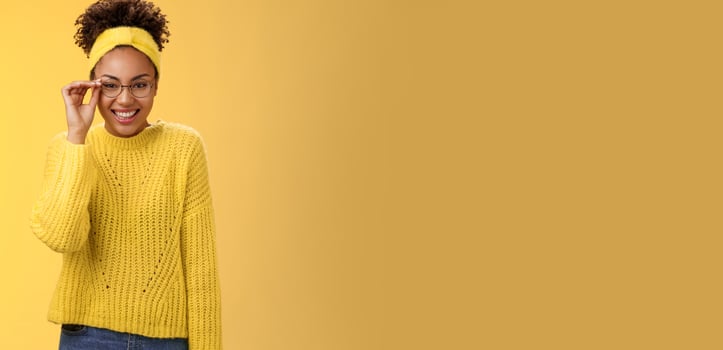 Cute clever best student college girl african-american touch glasses nose smiling broadly work part-time tutor children english lessons smiling friendly standing yellow background sweater, headband photo