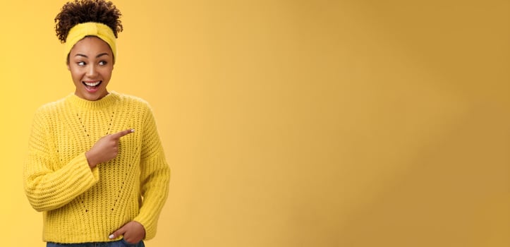Astonished cute feminine modern african-american woman gossiping silly laughing drop jaw laughing surprised pointing right discuss during conversation interesting rumour place, yellow background photo