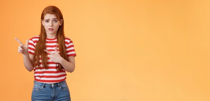 Insecure questioned frustrated cute redhead girl feel nervous unsure about suspicious offer frowning, grimacing doubtful and hesitant, pointing left look camera puzzled, asking question photo