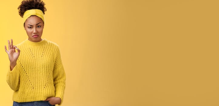 Well not bad. Portrait serious-looking confident arrogant young african-american woman agree effort good show okay ok normal gesture smug approval, standing yellow background impressed photo