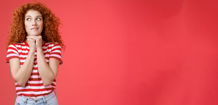 Cheerful intrigued redhead silly curly-haired woman smiling interested hold hands chin face-line imaging thinking about tasty burger look away desire have bite standing red background photo