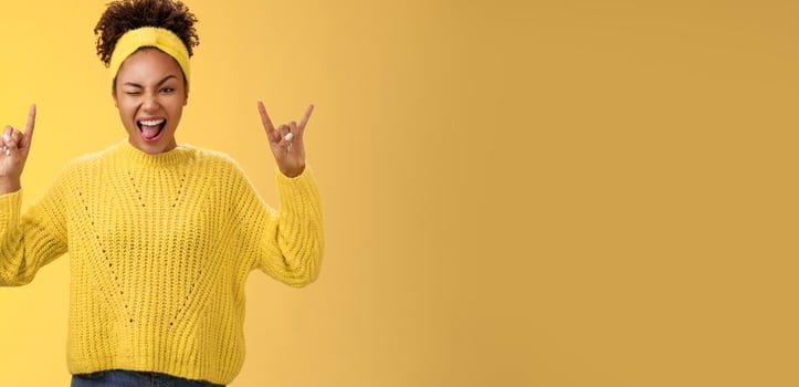Carefree cool stylish millennial african girl having fun chilling enjoying awesome music show tongue winking raise rock-n-roll heavy metal gesture feel incredibly happy excited visit concert photo