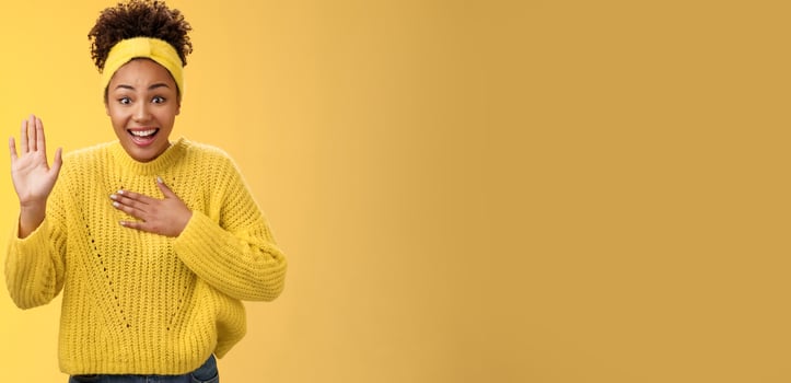 Fascinated amused young charming sincere african-american girl headband sweater press hand chest raise palm swearing promising do her best standing excited grinning happily, posing yellow background photo