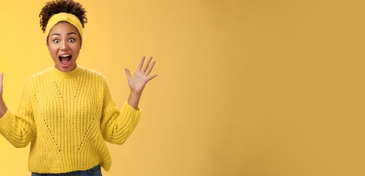 Excited happy stylish african woman in sweater yelling thrilled joyfully gesturing raised palms unbelievable luck triumphing receive extremely good perfect news, winning lottery, yellow background photo