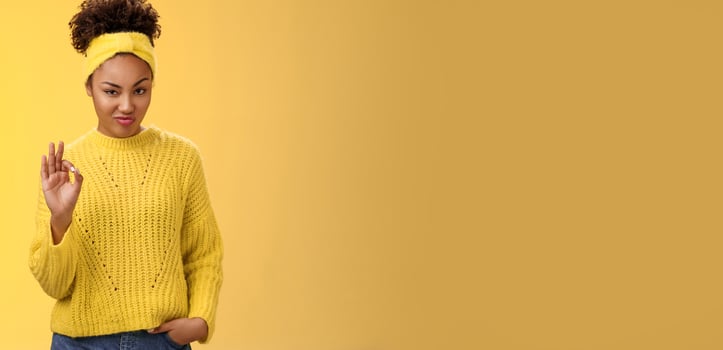 Okay not bad. Portrait devious serious-looking confident african-american bossy girl check out nice work done show ok gesture smug approval agree like good job, standing yellow background pleased photo