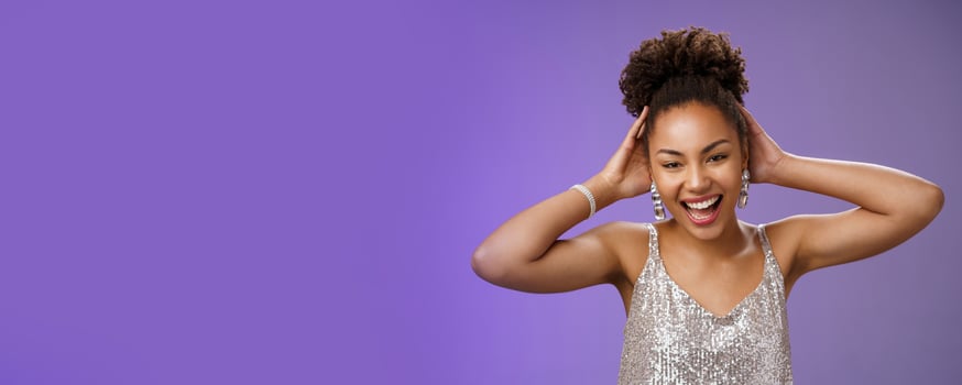 Joyful lucky african-american charming woman celebrating finish university enjoying party having fun dancing touching haircut optimistic smiling broadly enjoy wealthy lifestyle blue background photo