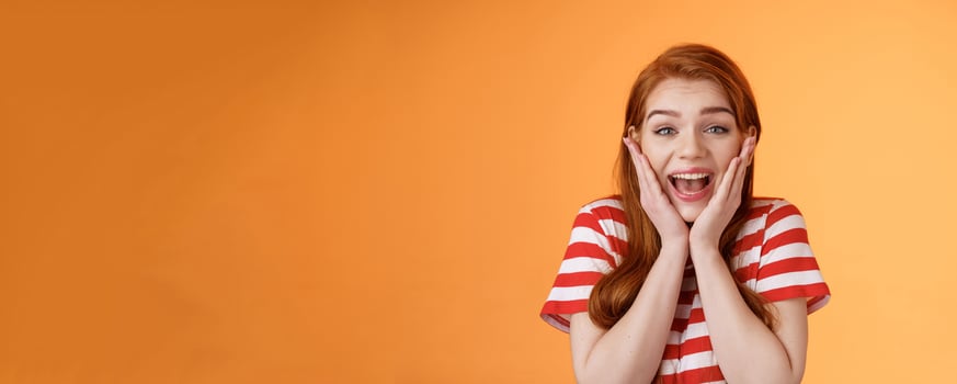 Close-up cute redhead cheerful girl look amazed yelling from joy lucky achieve best score, got scholarship, woman receiving stunning news, unbelievable success, smiling broadly, touch cheeks photo