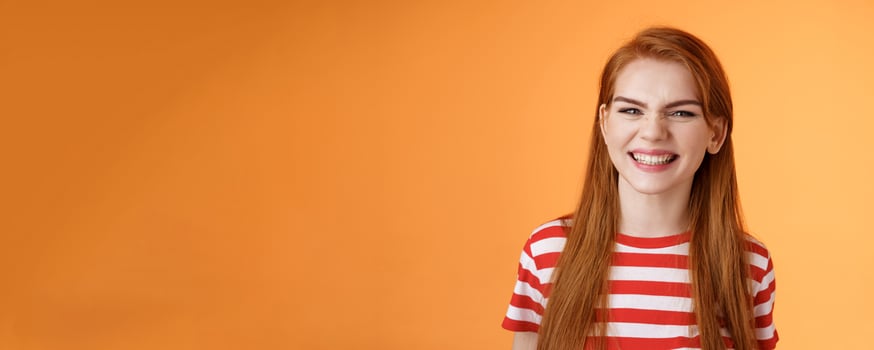 Close-up sassy good-looking cheerful redhead sly girl smiling toothy white perfect grin, satisfied dental clinic professional cleaning, standing orange background happy, joyful summer mood photo