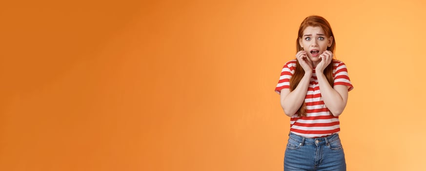 Innocent scared redhead female victim feel afraid standing stupor trembling fear, drop jaw gasping shocked, stare terrified, speechless look camera, frightened stand orange background photo