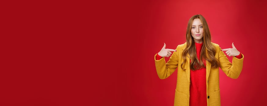 Self-assured assertive and optimsitic charming female entrepreneur with ginger hair in yellow coat pointing at herself proudly brag own success or willing to be candidate smiling confident photo