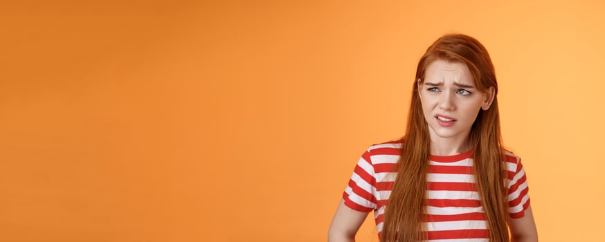 Close-up unsure redhead teenager frowning uncertain, having doubts, look perplexed left side copy space, hesitating, cringe dislike and disappointment, stare frustrated, uneasy decision photo