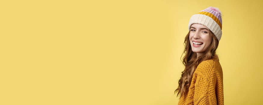 Profile shot charming carefree happy smiling girl turning camera grinning joyfully enjoying winter vacation having fun skiing, standing amused laughing wearing hat knitted sweater yellow background photo