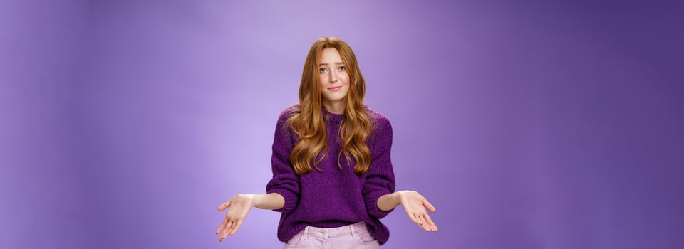Who cares chill I not know. Portrait of clueless and unbothered cute redhead female in purple sweater smirking in sorry and shrugging with hands sideways being questioned and puzzled to answer photo