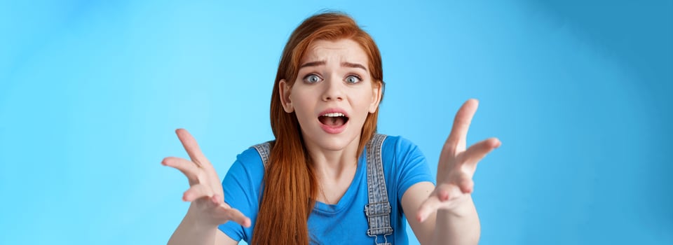 Close-up uneasy disappointed cute gloomy redhead girl, raise hands dismay full dibelief, frowning gasping upset, losing competition, receive bad results, stand blue background unhappy photo