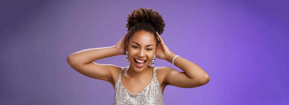 Joyful lucky african-american charming woman celebrating finish university enjoying party having fun dancing touching haircut optimistic smiling broadly enjoy wealthy lifestyle blue background photo