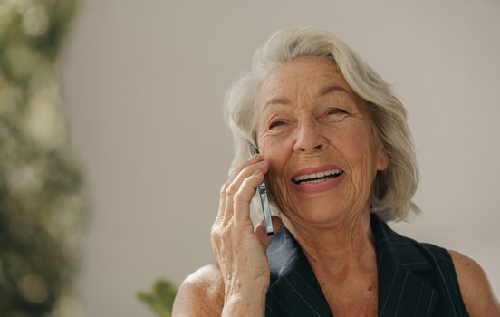 A Joyful Elderly Woman Engaged in a Cheerful Phone Conversation While Outdoors in Daylight photo