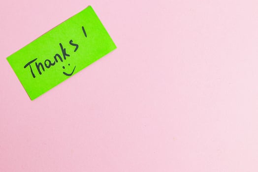 Green small note with the word thank you on a pink background photo