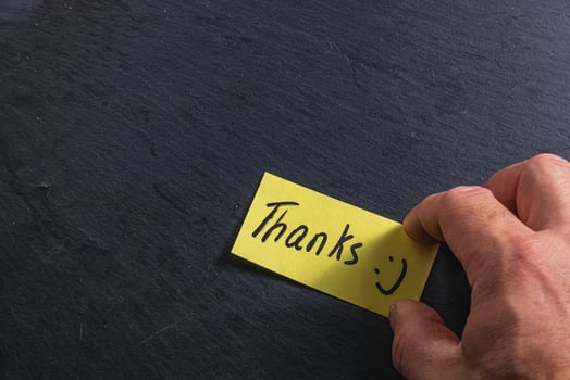 The man is holding a piece of paper with the word thank you in his right hand photo