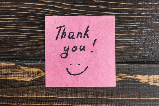 The word thank you on a pink leaf on a brown wooden table photo