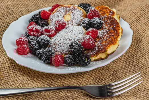 Cottage cheese pancakes with fresh raspberries, blackberries and powdered sugar photo