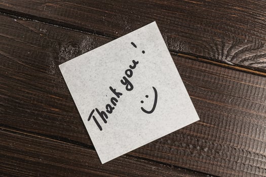 White thank you note on wooden table photo