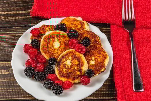 Fresh cottage cheese pancakes with raspberry blackberry on a white plate photo
