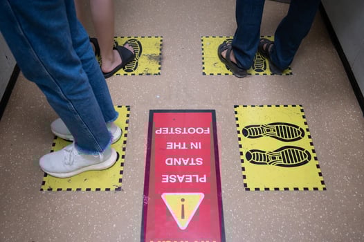 Foot of peoples standing on yellow footprint sign in lift or elevator and keep space for avoid spreading of virus disease in covid-19 pandemic. Social distancing puts space between people. photo