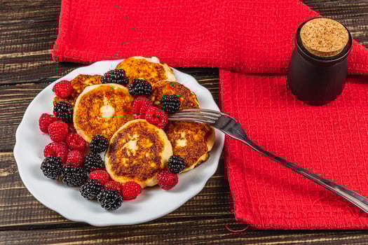 Fresh cottage cheese pancakes with raspberry blackberry on a white plate photo