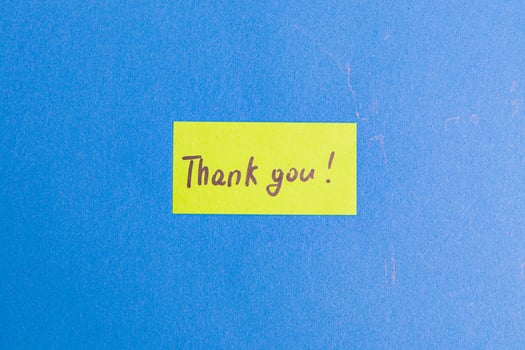 A small yellow note with the word thank you on a blue background photo