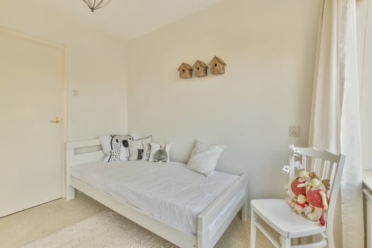 A bedroom with a bed, chair and window photo