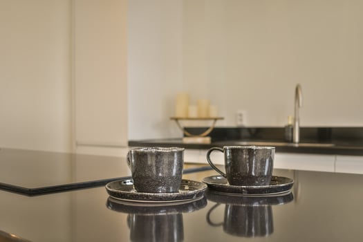 Two coffee cups sit on a black counter top photo