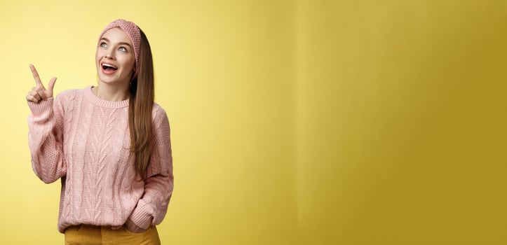 Amused and impressed dreamy pretty young european woman in knitted sweater gasping entertained dropping jaw smiling thrilled, joyful, pointing, looking at upper left corner excited of awesome promo photo