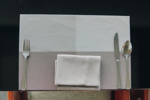 A silverware set is placed on a table with a napkin, set for a meal. photo