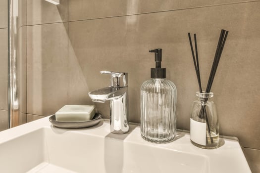 A bathroom sink with a glass bottle and a bottle of soap photo