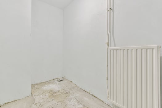 An empty room with a radiator and a wall photo