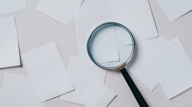 Magnifying glass over a pile of white paper documents photo