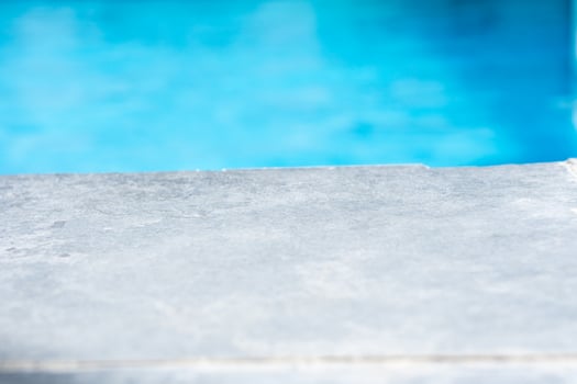 Empty grey ceramic table top and blurred swimming pool in tropical resort in summer banner background photo