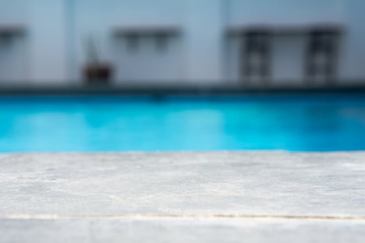 Empty grey ceramic table top and blurred swimming pool in tropical resort in summer banner background photo
