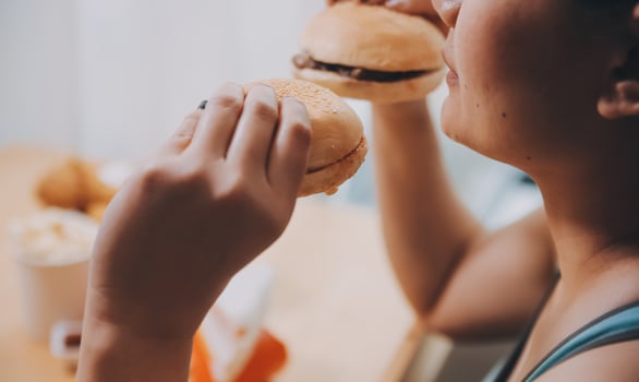 Binge eating disorder concept with woman eating fast food burger, fired chicken , donuts and desserts photo